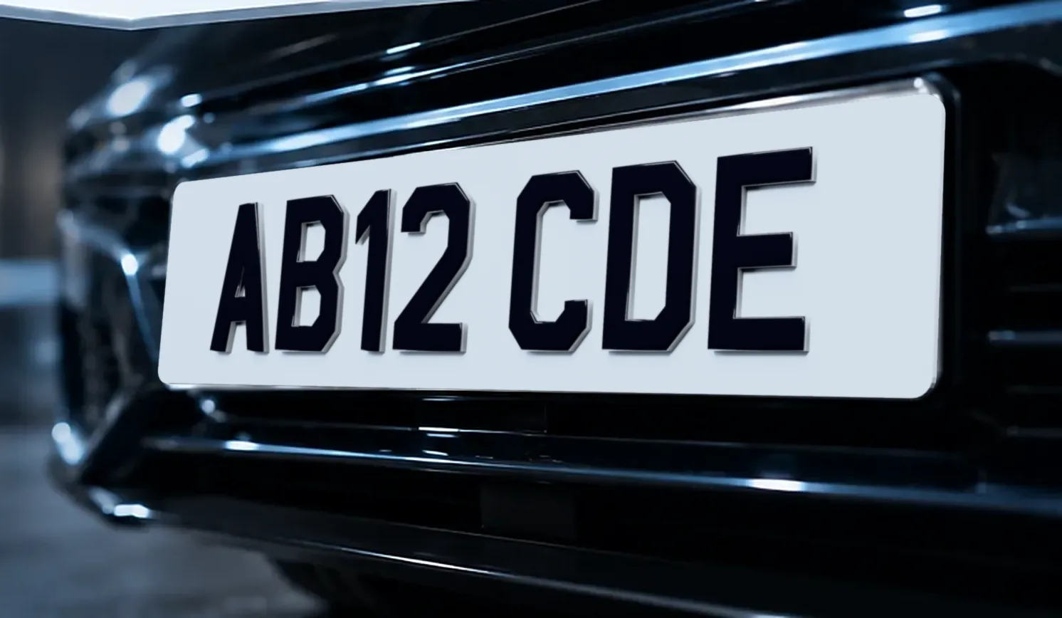 The front of a dark car fitted with a white 5D number plate