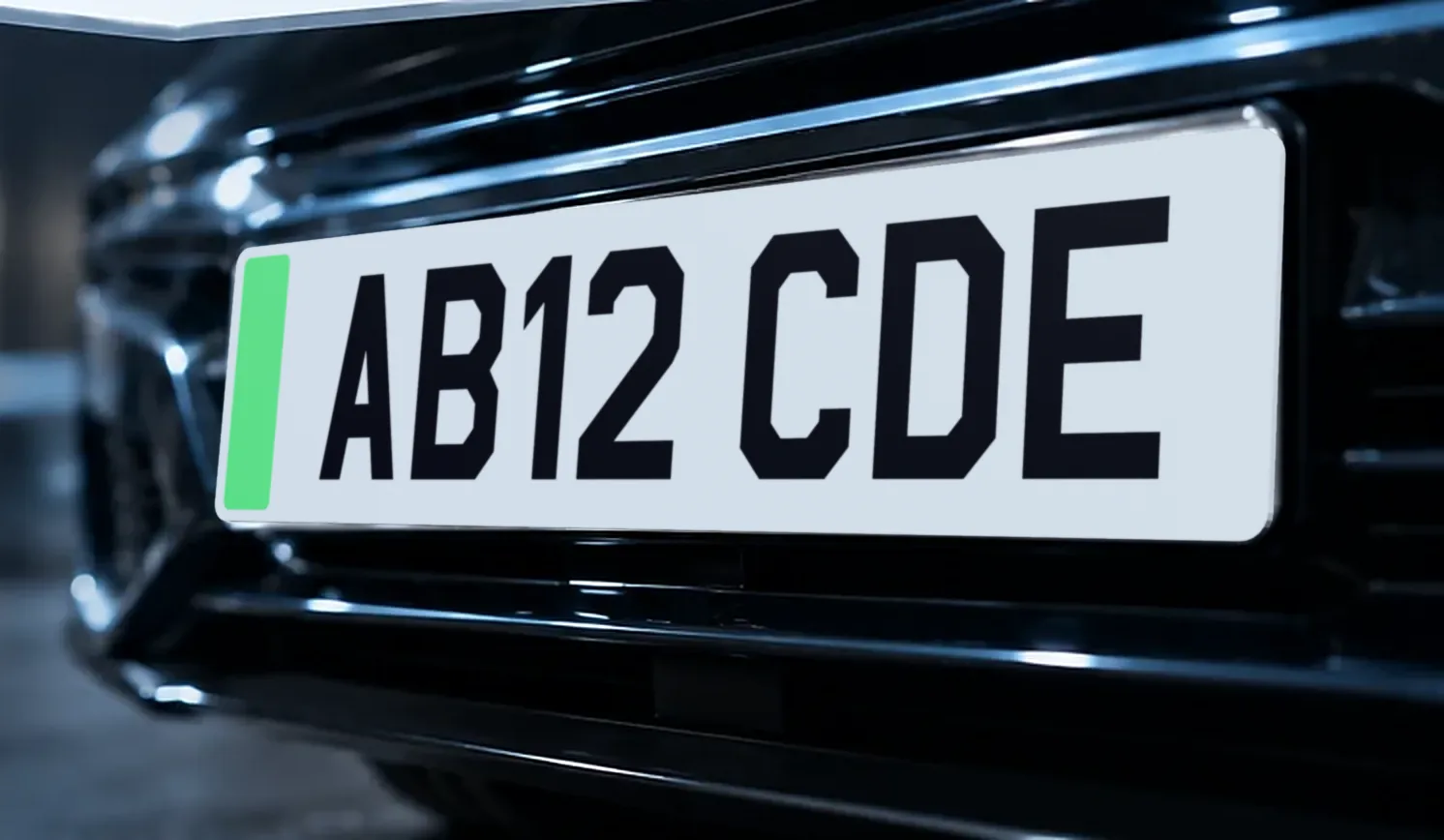 The front of a dark car fitted with a white EV number plate